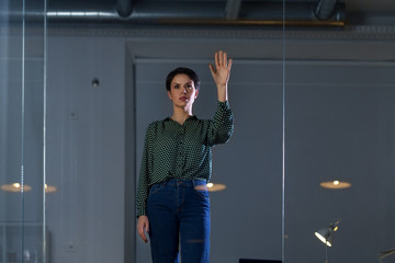 business, technology and people concept - businesswoman working and touching glass wall at night office