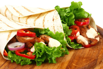 Tortilla wrap with fried chicken meat and vegetables on wooden board isolated on white background