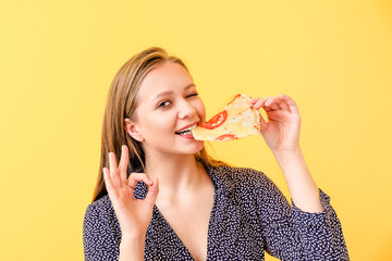 Beautiful woman eating tasty pizza on color background