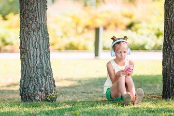 Little adorable girl listening music in the park