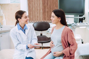 Fototapeta premium Female ultrasonographer working with pregnant woman in modern clinic