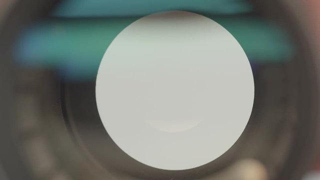 Close-up shot of opening shutter in the objective of videocamera with blue reflections in it.