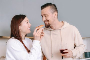 Happy couple drinking wine and eating tasty pizza at home