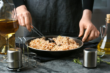 Woman cooking tasty risotto at table