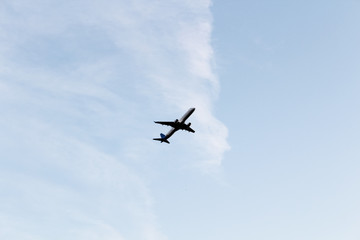 Airplane flying in a clear pale blue sky. Cloudy background