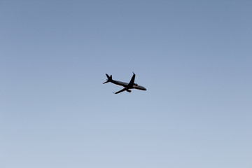 Airplane flying in dark blue evening sky. Plane on pure sky background