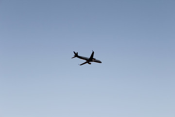 Fototapeta na wymiar Airplane flying in dark blue evening sky. Plane on pure sky background
