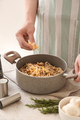 Woman cooking tasty risotto at table