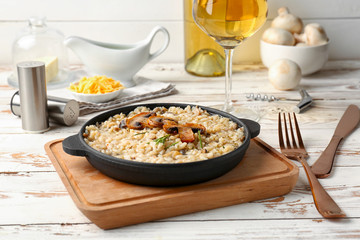 Frying pan with tasty risotto on wooden table