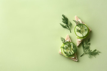 Tasty sandwiches with cucumber on color background