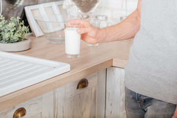 Dairy products. Healthy lifestyle. Cropped shot of man taking glass of soy milk. Kitchen background.