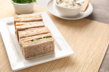 Plate with tasty cucumber sandwiches on table