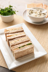 Plate with tasty cucumber sandwiches on table