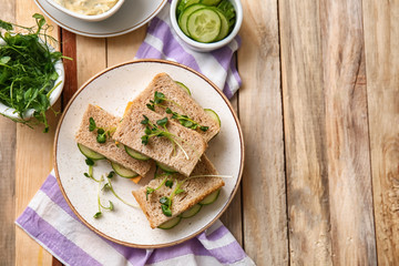 Plate with tasty cucumber sandwiches on wooden table