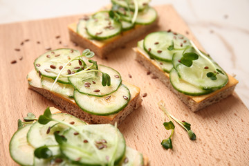 Tasty cucumber sandwiches on wooden board, closeup