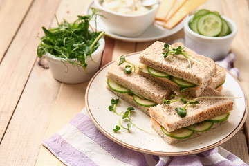 Plate with tasty cucumber sandwiches on wooden table