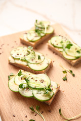 Tasty cucumber sandwiches on wooden board