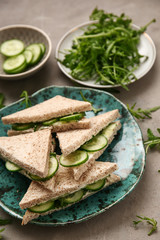 Plate with tasty cucumber sandwiches on grey background