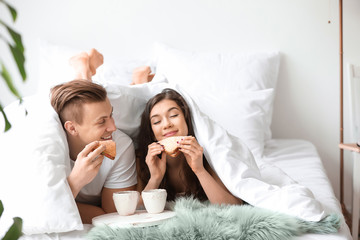 Cute young couple having breakfast in bed