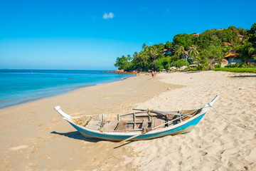 Fototapeta na wymiar Tropical landscape with boat at sand beach, blue sky and turquoise sea