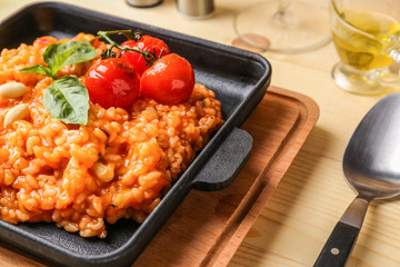 Frying pan with tasty risotto on wooden table