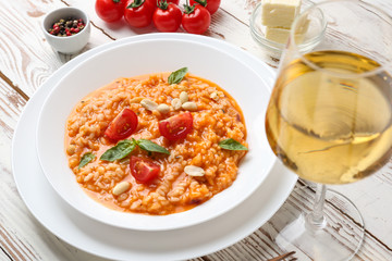 Plate with tasty risotto and glass of wine on wooden table