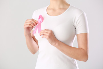 Young woman with pink ribbon on white background. Breast cancer awareness concept