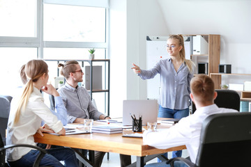 Young businesswoman giving presentation at meeting in office