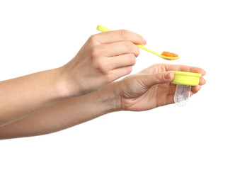 Mother putting fresh food into baby nibbler on white background