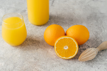 Top view of fresh oranges and fresh orange juice in glass, wooden juicer on white table. Multifruit...