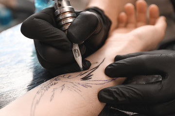 Professional artist making tattoo in salon, closeup