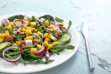 Plate with tasty mango salad on table