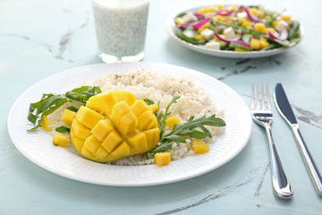Plate with tasty rice and mango on table