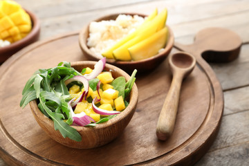 Bowl with tasty mango salad on wooden table