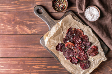 Tasty beet chips on wooden table