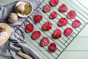Cooling rack with tasty raw beet chips on wooden table