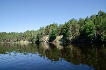 River Bank with slopes and trees growing on the edge near the water