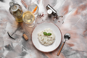 Plate with tasty risotto and wine on color background