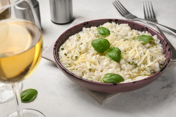 Plate with tasty risotto and glass of wine on table