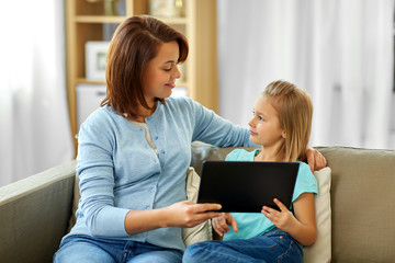 people, family and technology concept - happy mother and daughter with tablet pc computer at home