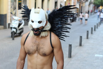 Man wearing dark wings, dog mask and gag ball outdoors 