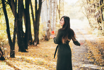 Dreamy dancing girl with long natural black hair on autumn background with trees and yellow leaves...