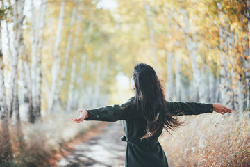 Dreamy beautiful girl with long natural black hair flies on bokeh background of autumn yellow...