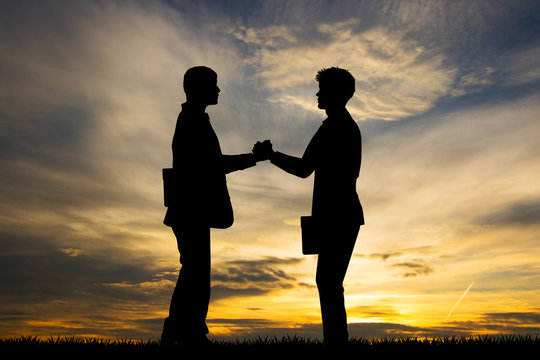 businessmen shake hands at sunset