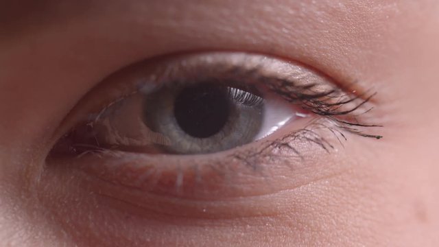 Close-up shoot of blue eye blinking with the reflection and flare on it.