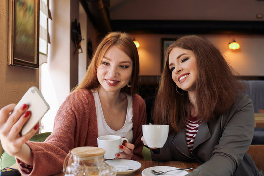 Beautiful young women taking selfie in cafe