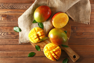 Board with tasty fresh mango on wooden table