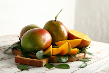 Board with tasty fresh mango on wooden table