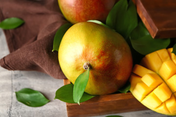 Wooden box with tasty sweet mango on grey background
