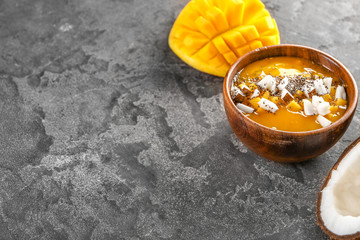 Bowl with tasty mango smoothie on grey background